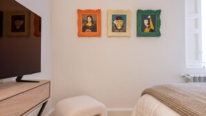 A bedroom with a bed, a TV, and three framed artworks on the wall. - Waou Justicia VI - Short-Term Rental (Madrid)
