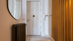 A hallway with a radiator, a door with a lock, and a wooden panel wall. - Waou Justicia VI - Short-Term Rental (Madrid)