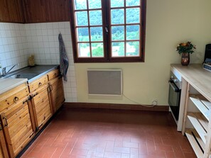 Una cocina con ventana, armarios de madera, salpicadero de azulejos y piso de baldosas.