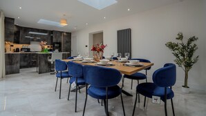 A modern dining area with a skylight, a kitchen in the background, and a potted plant. - Spacious 5Bed House in Ruislip Sleeps 10 (Ruislip)