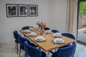 A dining area with a wooden table set for four, blue chairs, and a vase with flowers.