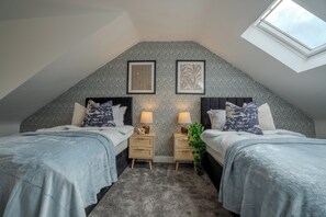 A bedroom with two beds, a skylight, and patterned wallpaper.