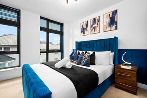 Ein modernes Schlafzimmer mit einem großen Bett, einem Nachttisch und einem Fenster mit Jalousien.