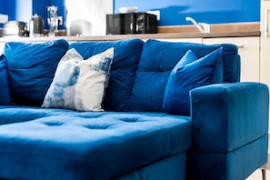A blue sofa with a single decorative pillow in a modern living room. - Luxury 2 Bed Apartment - Parking - JQ - City Centre - Bedroom TV (West Midlands)
