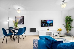 A modern living room with a dining area, a flat-screen TV mounted on the wall, and a large potted plant. - Luxury 2 Bed Apartment - Parking - JQ - City Centre - Bedroom TV (West Midlands)