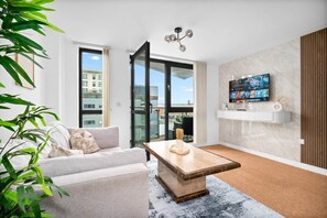 Un salon moderne avec un canapé, une table basse et un téléviseur fixé au mur.