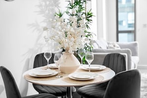 Une table à manger dressée avec des assiettes, des verres et un vase rempli de fleurs blanches.