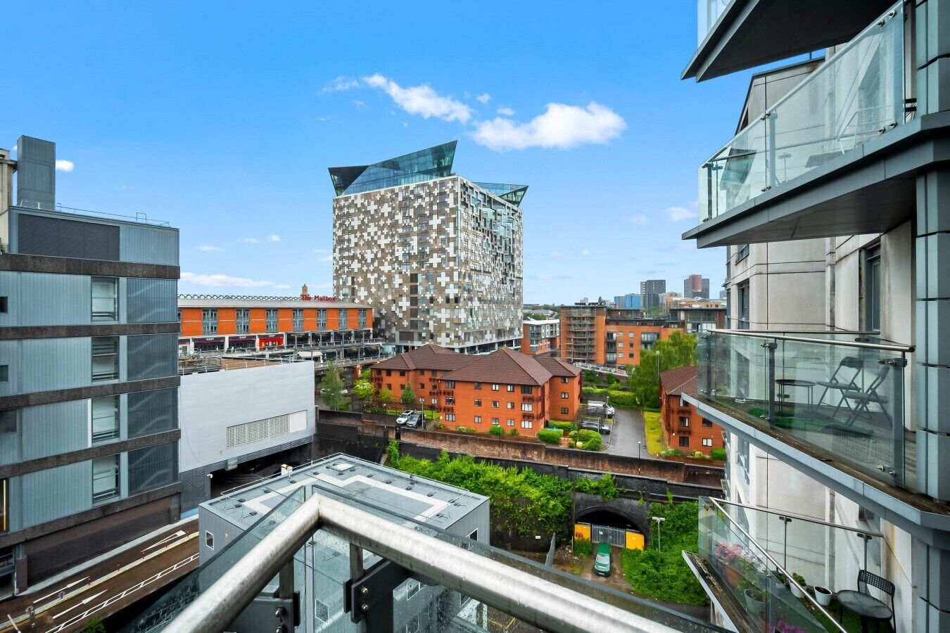 A modern building with a unique geometric facade, surrounded by other contemporary structures.