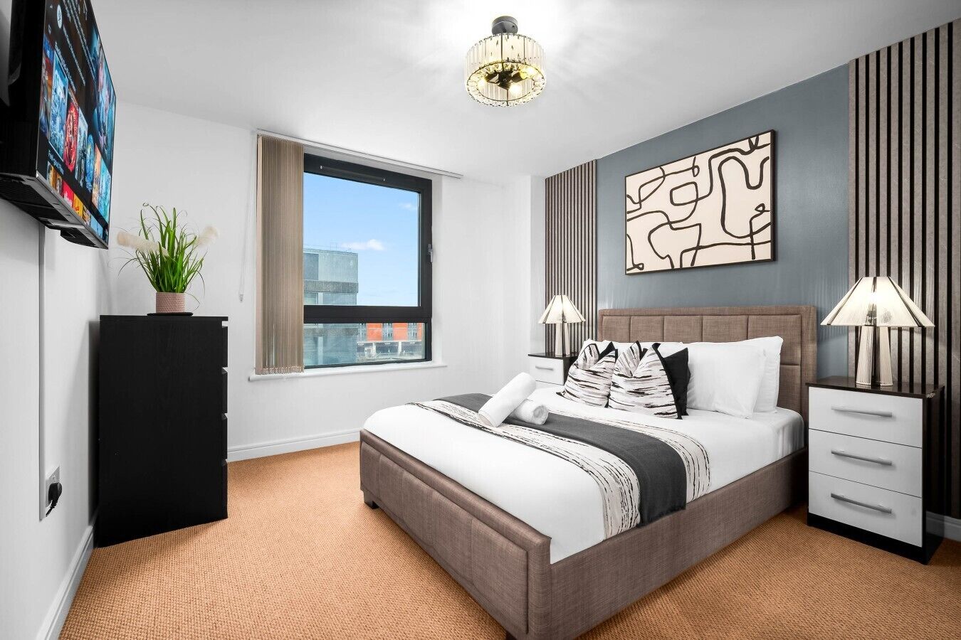 Ein modernes Hotelzimmer mit einem großen Bett, einem Flachbildfernseher, einer Zimmerpflanze, einem Fenster mit Blick und einem Wandbild.