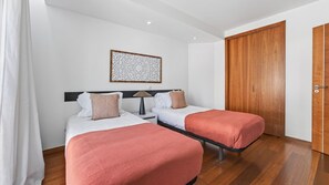 Ein Hotelzimmer mit zwei Betten, einem Nachttisch, einer Lampe, einem Wandbild und einem Holzschrank.