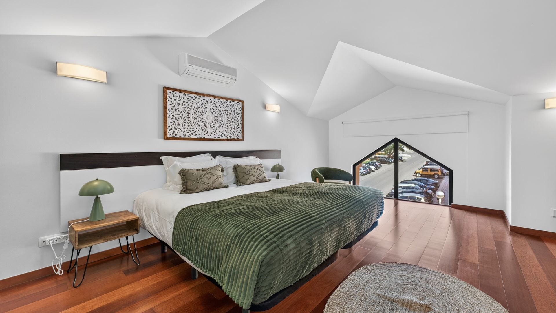 A modern bedroom with a large bed, a nightstand, a lamp, and a decorative wall piece.