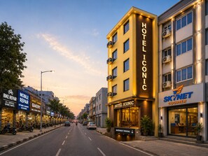 A hotel named 'Hotel Iconic' with a modern facade, located on a street with various shops and a visible 'SkyNet Courier' sign. - Hotel Iconic Suite near Delhi Airport (New Delhi)