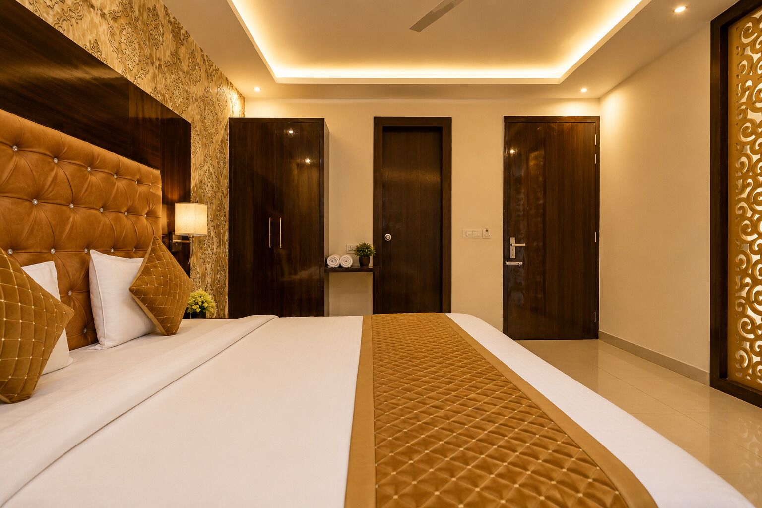 A modern hotel room with a large bed, dark wooden wardrobe, and a decorative wall panel.