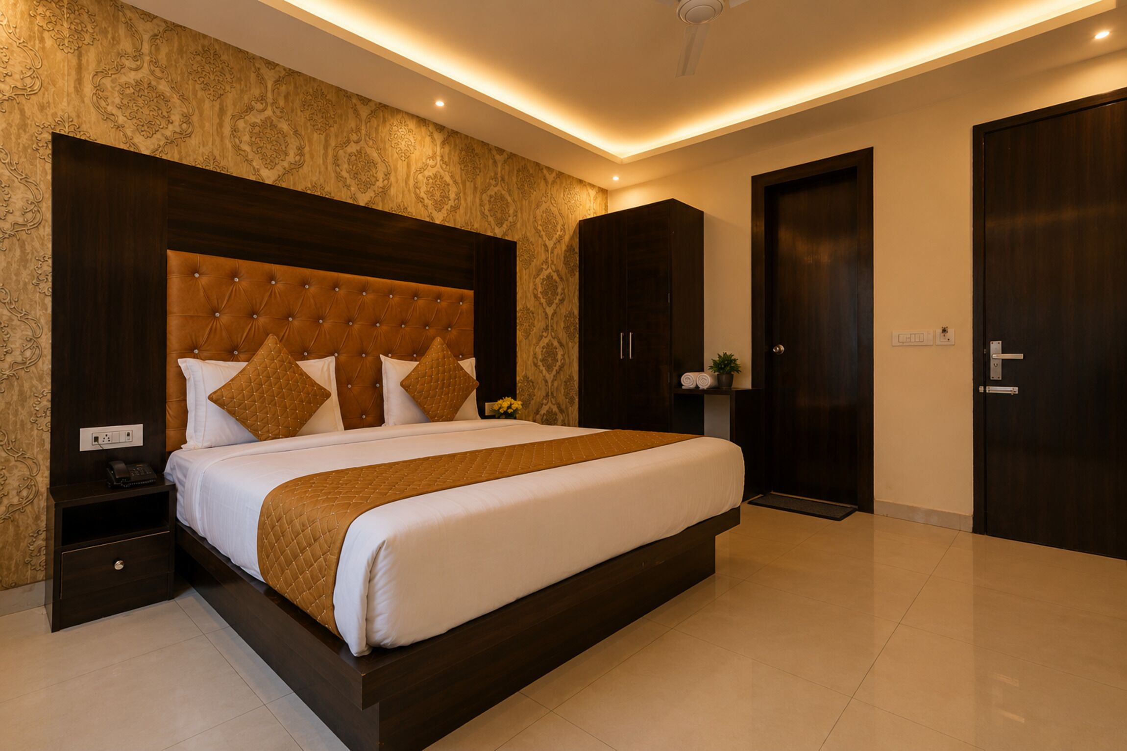 A hotel room with a large bed, a wardrobe, a nightstand, and a ceiling fan.