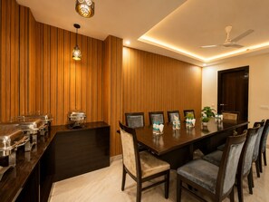 A conference room with a long table, chairs, a ceiling fan, and a wooden wall paneling. - Hotel Iconic Suite near Delhi Airport (New Delhi)