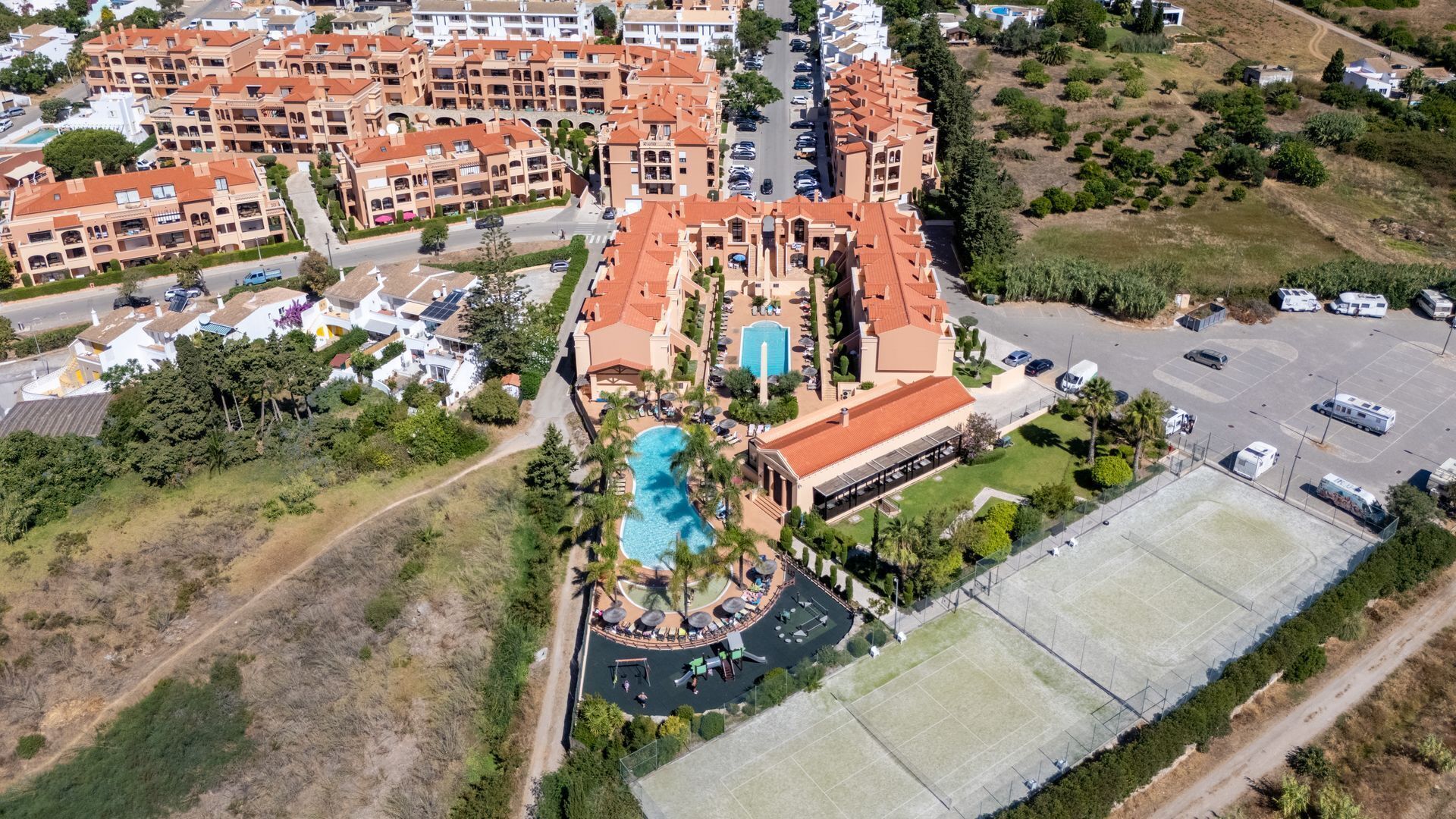 Ein Luftbild zeigt ein Resort mit mehreren Gebäuden, einem Schwimmbad und einem Parkplatz.