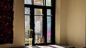 A room with a large window, a patterned carpet, a small table, and a decorative item on the windowsill.