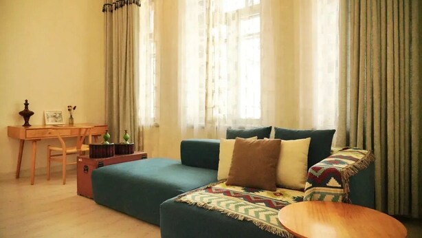 A living room with a sofa, a small wooden table, a desk, and a chair.