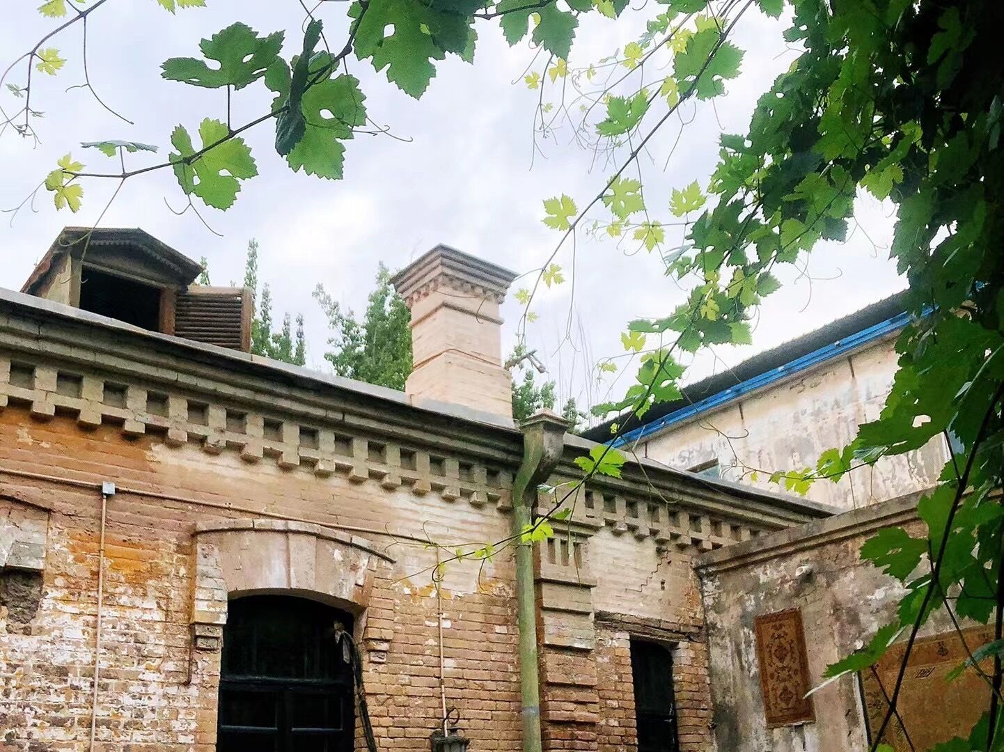 Un edificio antiguo de ladrillo con un diseño tradicional, que presenta un arco central como entrada y una ventana pequeña.