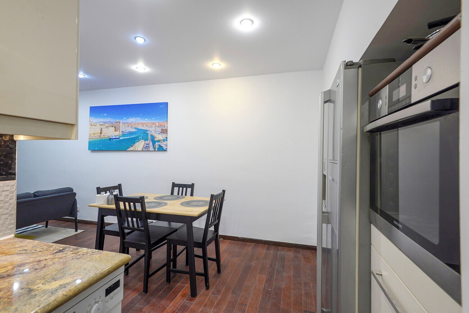 Une cuisine compacte avec un coin repas, un réfrigérateur et un tableau accroché au mur.