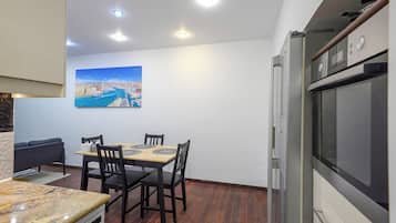 Una cucina compatta con zona pranzo, un frigorifero e un quadro appeso al muro.