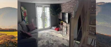 A living room with a sofa, a coffee table, and a TV mounted on the wall.