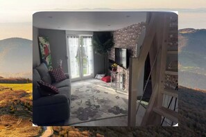 A living room with a sofa, a coffee table, and a TV mounted on the wall. - The Rabbits of the Vosges! (SAULCY SUR MEURTHE)