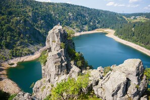 A rocky cliff overlooking a calm lake with dense forested hills in the background. - The Rabbits of the Vosges! (SAULCY SUR MEURTHE)