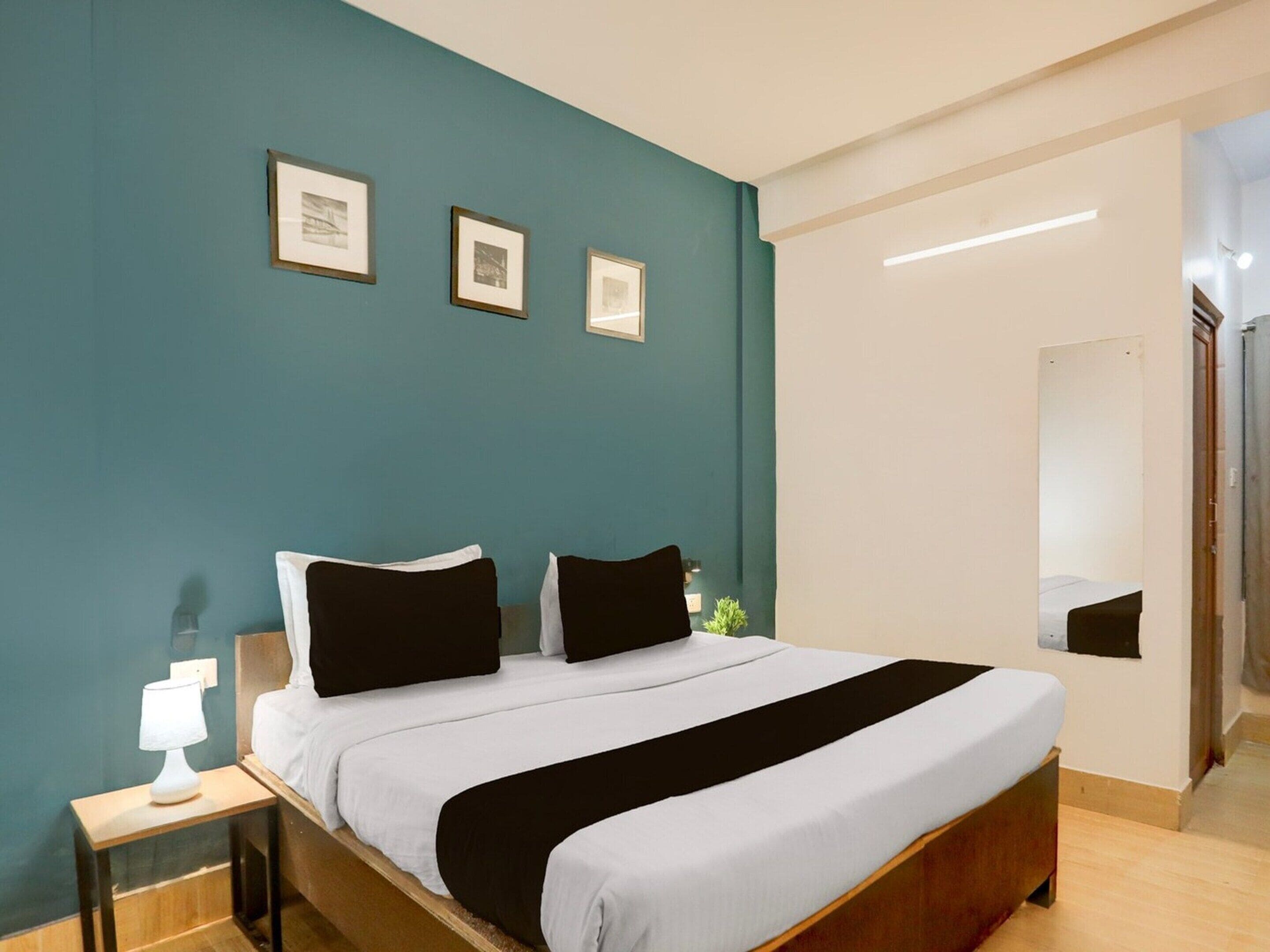A bedroom with a bed, a nightstand, and a wall-mounted mirror.