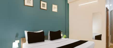 A bedroom with a bed, a nightstand, and a wall-mounted mirror.