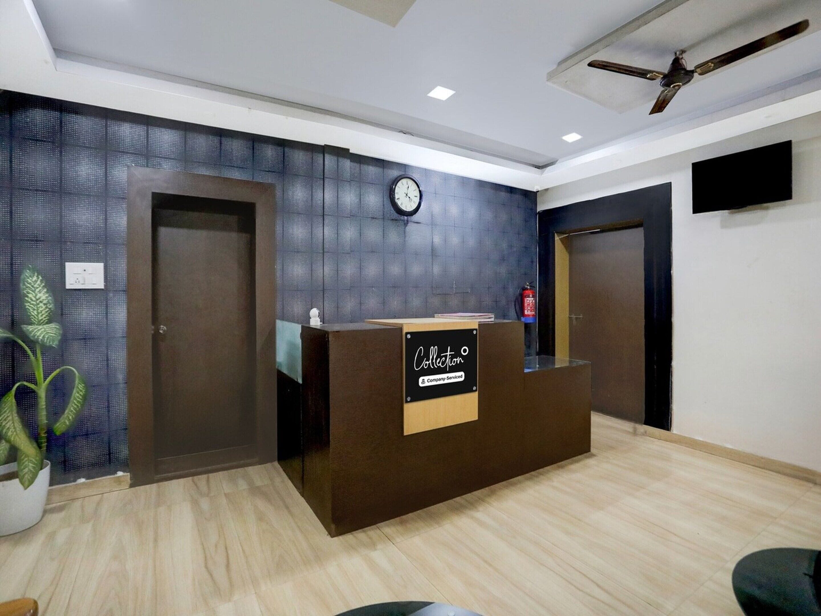 A reception area with a wooden reception desk, a clock on the wall, and a ceiling fan.
