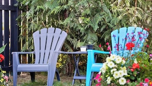 Due poltrone Adirondack, un tavolino e diversi fiori in un giardino.