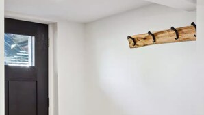 Una stanza con una panca in legno, un appendiabiti e una porta.