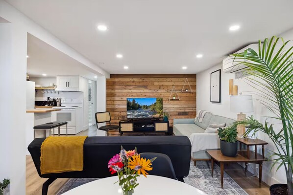 A modern living room with a television, sofa, and dining area.