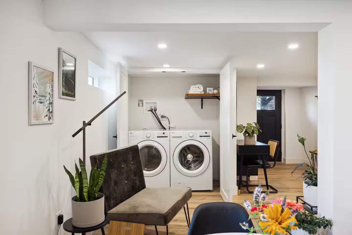 A modern apartment with a laundry area, a dining table, and a sofa.
