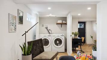 A modern apartment with a laundry area, a dining table, and a sofa.