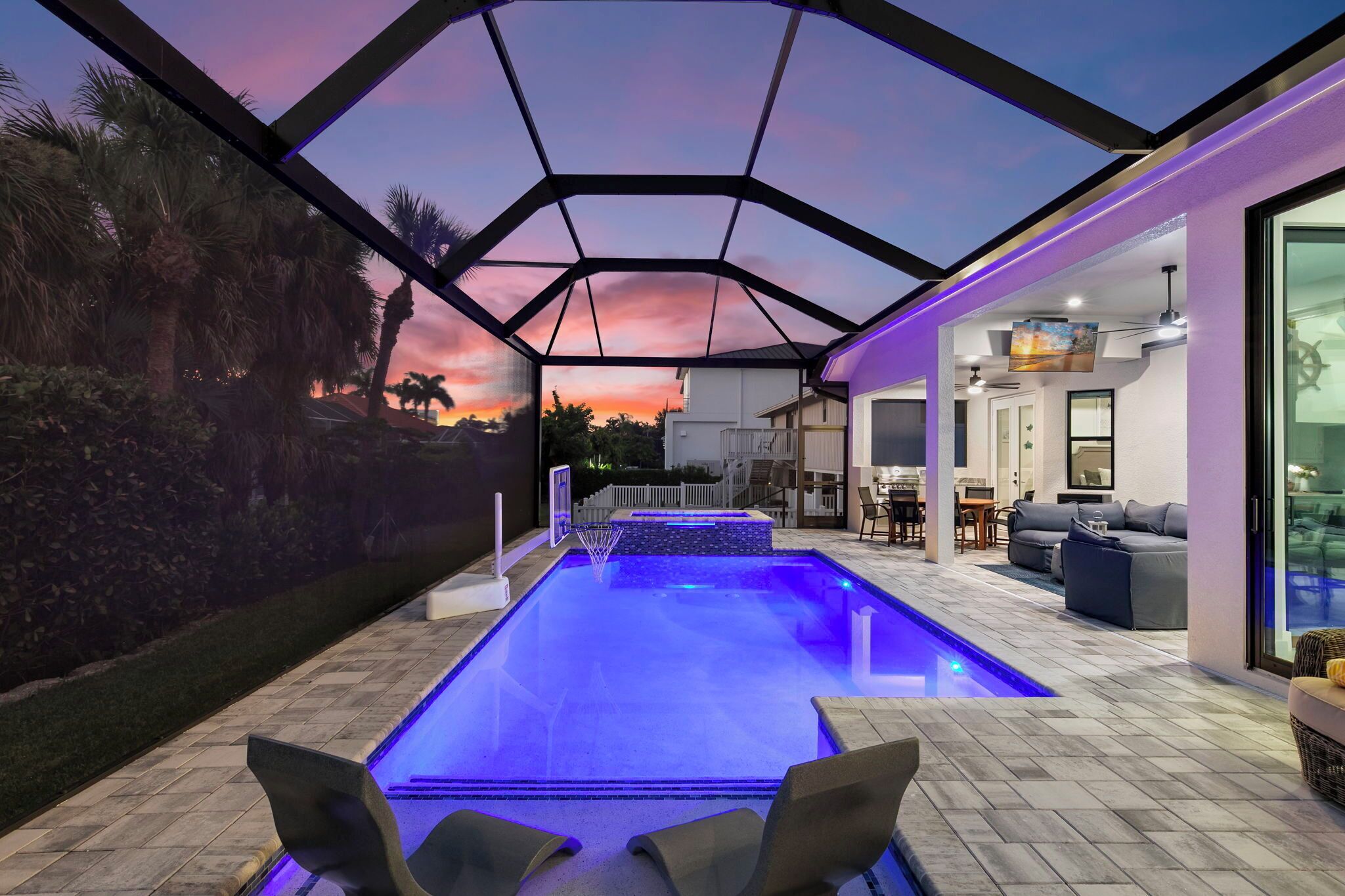 Una piscina con techo de cristal, un comedor y vista al atardecer.