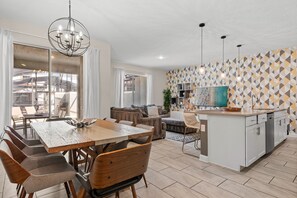 Una cocina moderna con comedor, una araña y una pared con diseño geométrico.