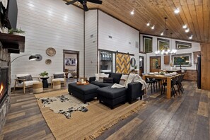 Ein modernes Wohnzimmer mit Kamin, Essbereich und Küche mit Holzschränken.