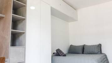 Een slaapkamer met een bed, een kledingkast en een plafondventilator.