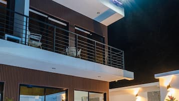 Een modern huis met twee verdiepingen, een balkon, zitplaatsen buiten en een zwembad.