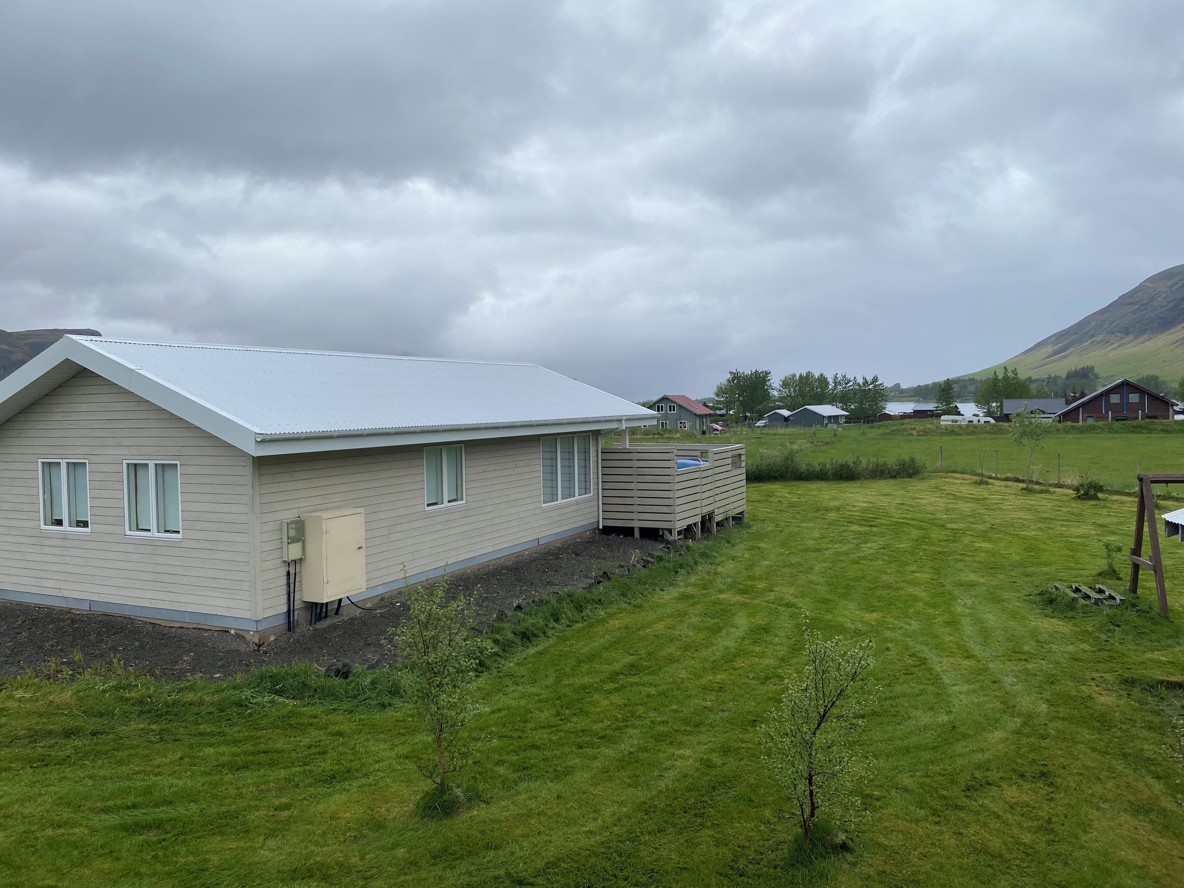 A single-story house with a sloped roof, a small shed, and a grassy yard.