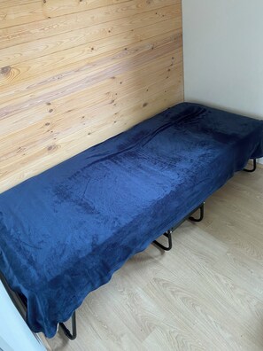 A room with a wooden panel wall, a blue bench, and a light-colored wooden floor.