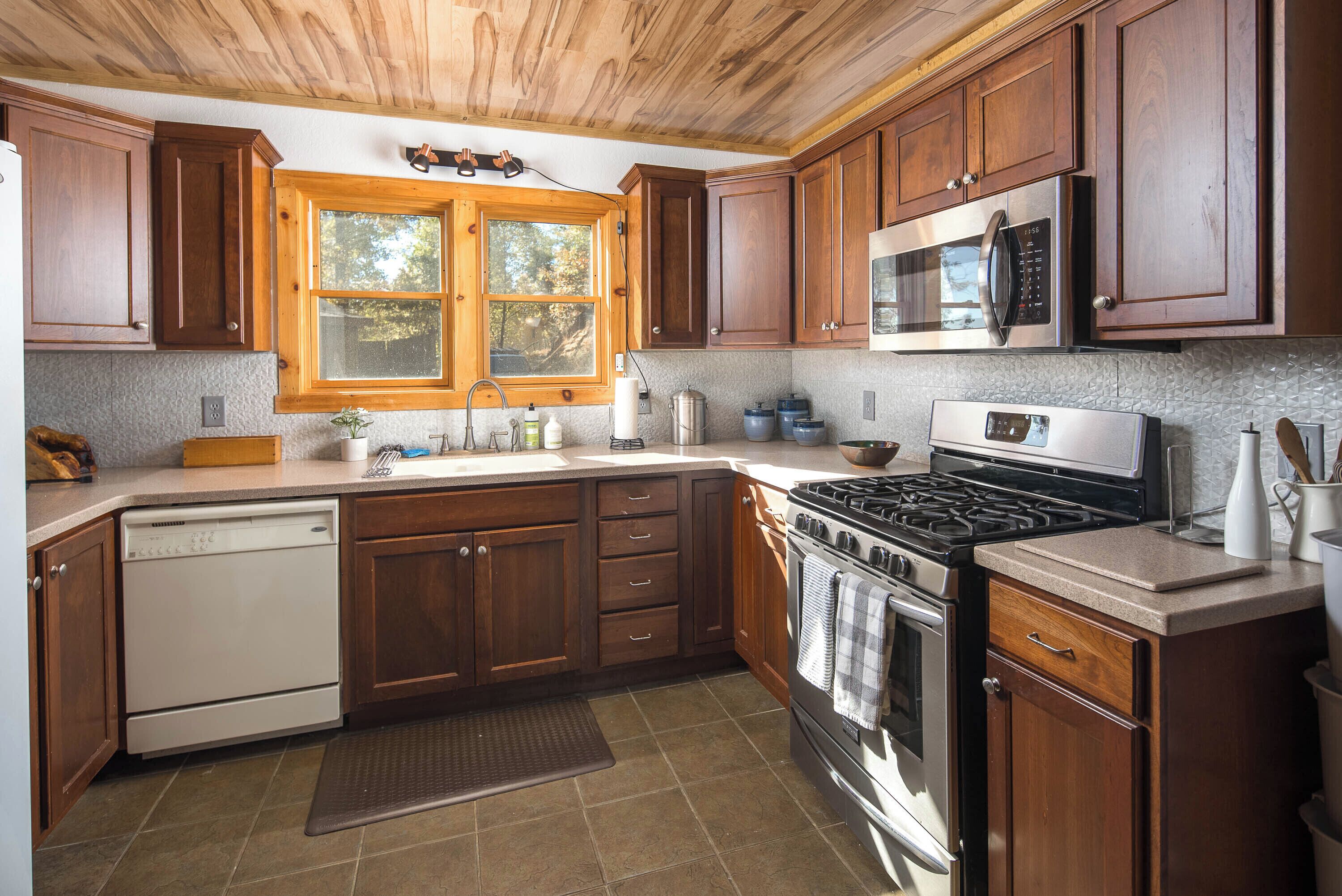 A kitchen with wooden cabinets, a stainless steel stove, a microwave, and a dishwasher.