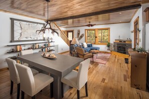 A spacious living area with a dining table, sofas, and a fireplace. - Whisper Ridge 3BR Deep Gap Cabin · Mountain Views · Fire Pit · Sleeps 9 (Watauga County)