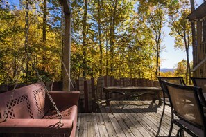 An outdoor deck with a wooden bench and a cushioned seating area. - Whisper Ridge 3BR Deep Gap Cabin · Mountain Views · Fire Pit · Sleeps 9 (Watauga County)