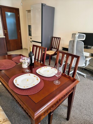 A dining table set with plates, a bottle, and glasses, surrounded by chairs. - Delightful 2-bedroom apartment with AC in charming Bansko (Bansko)