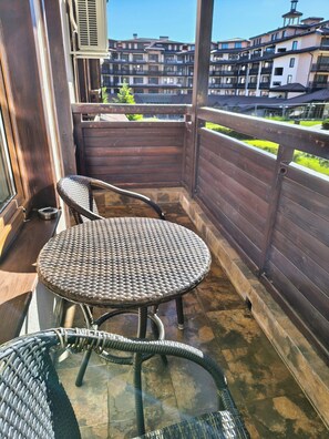 A balcony with wicker furniture, a view of buildings, and a wooden fence. - Delightful 2-bedroom apartment with AC in charming Bansko (Bansko)