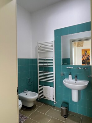 Ein Badezimmer mit einer Bidet-Funktion, einem Waschbecken, einem Spiegel und einem Handtuchhalter.