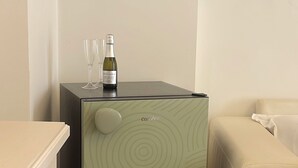 Een compacte koelkast met een cirkelpatroon, een fles wijn en twee glazen erop.